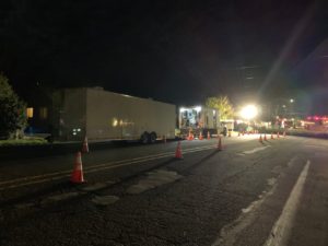 large truck parked on street at night with orange traffic cones